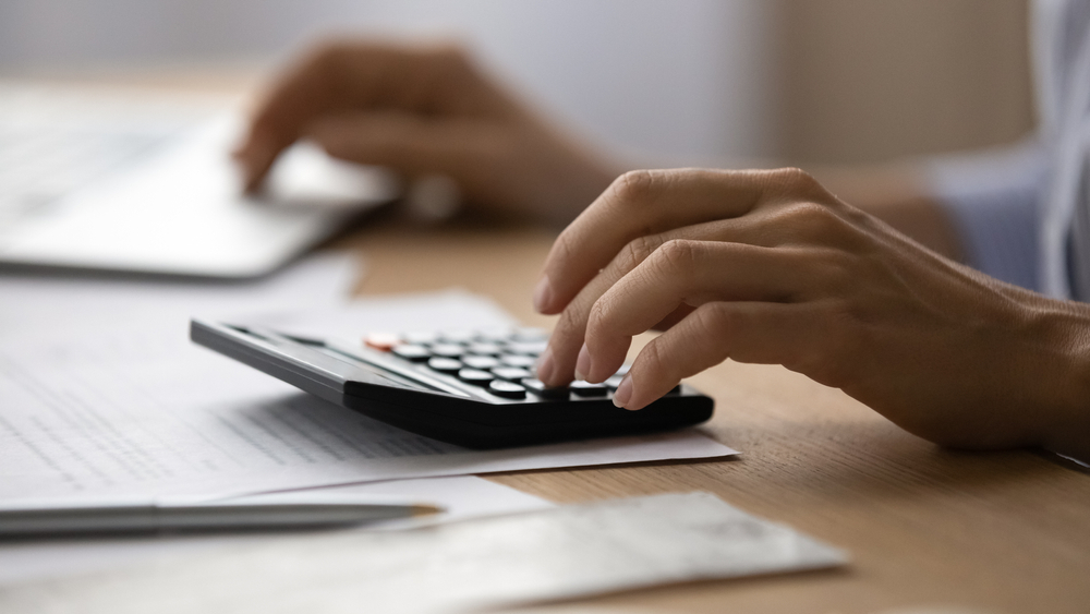 A person using a calculator, sat at a desk.