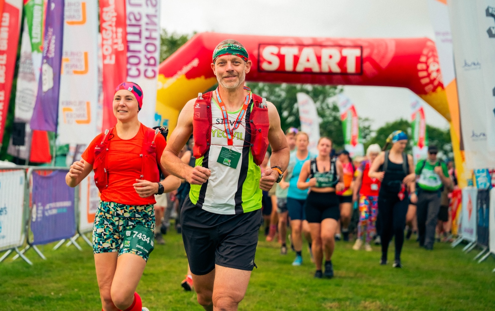 Runners starting a race under a red arch marked 'START,' with colourful banners around.