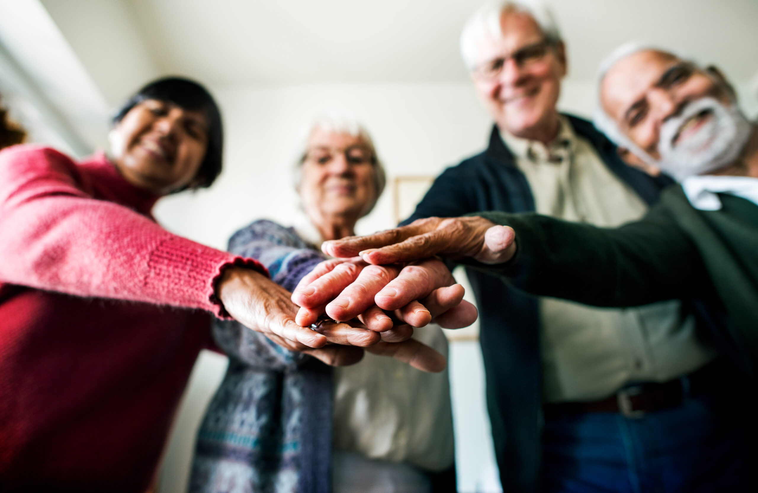 A group of people standing in a circle with their hands stacked together in the centre.